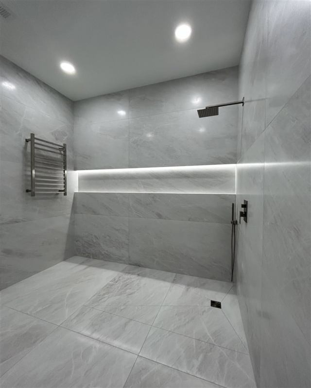 Marble-look walk-in shower with LED-lit niche and towel warmer