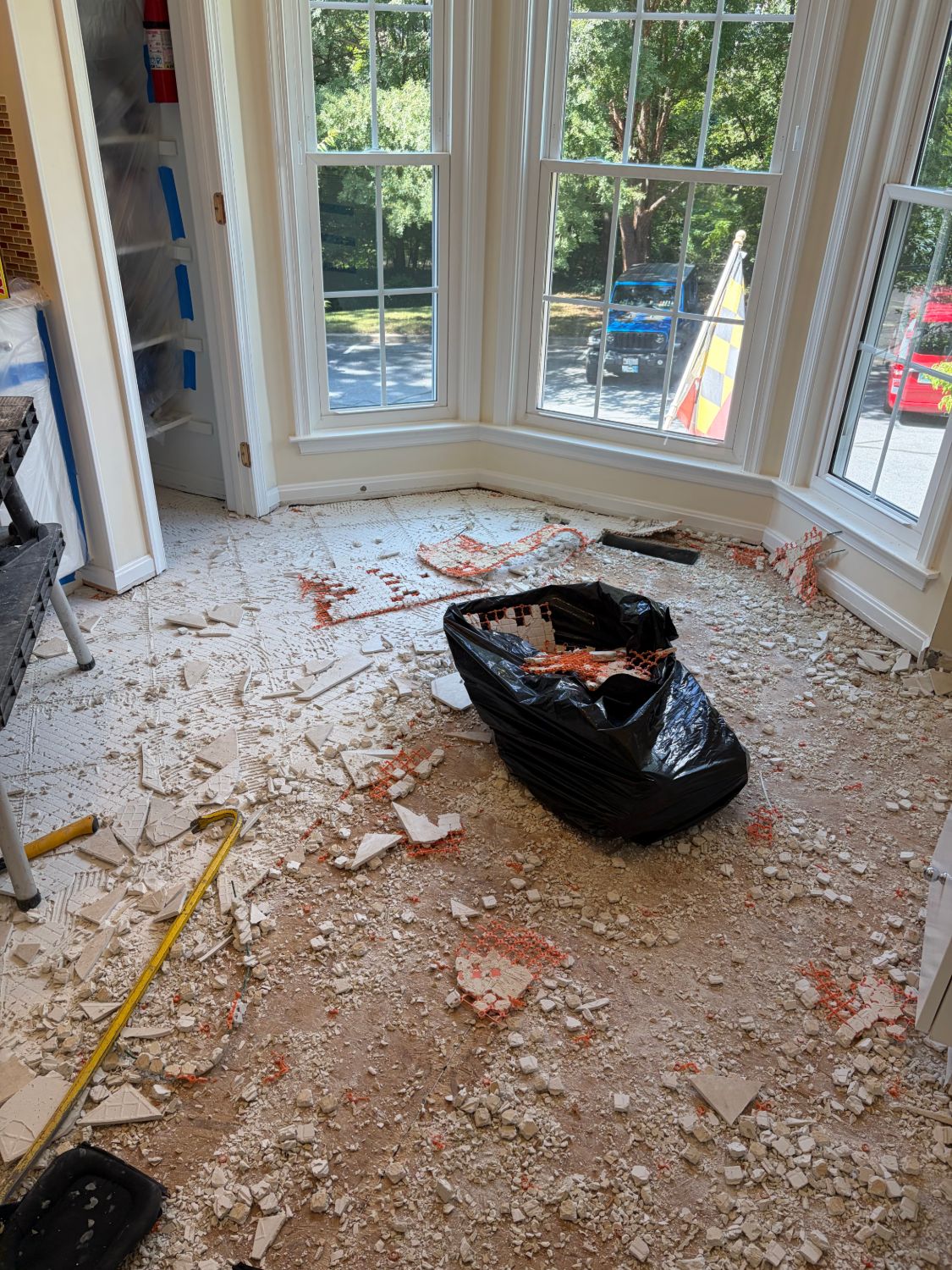 Bay window area before — old tile demolished, debris on subfloor